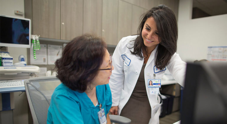 Physician speaking with staff member by desk