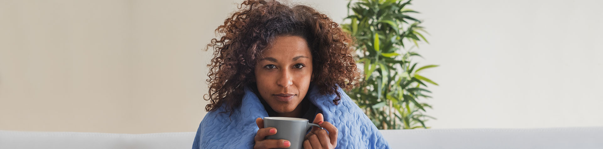 Woman under blanket with mug