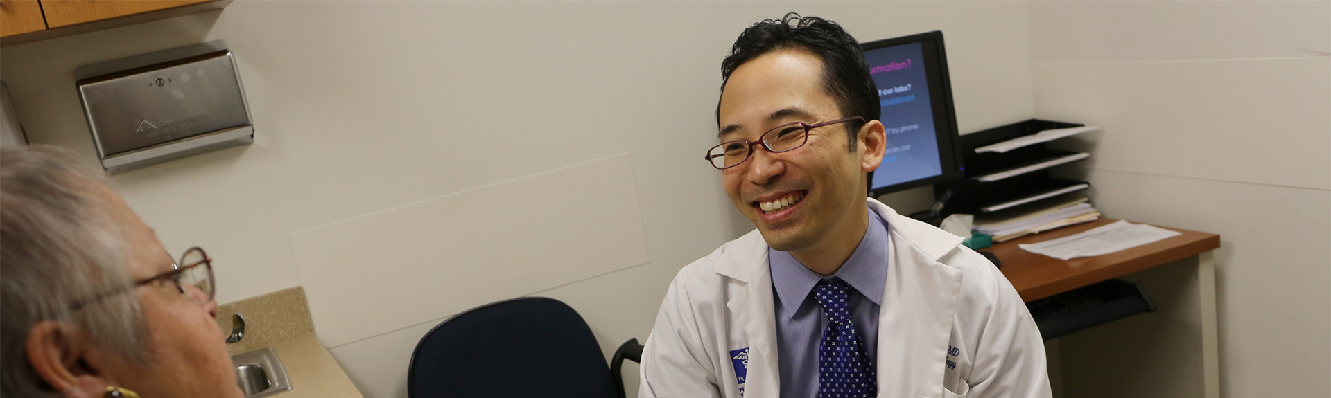 male physician and female patient talking in an exam room