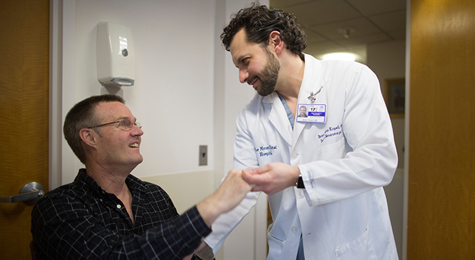 doctor consolidating patient while he sits down smiling at each other