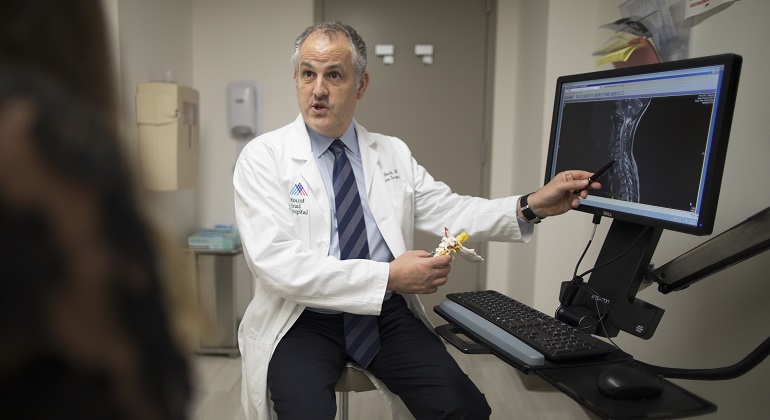 Image of doctor showing patient spine image in computer screen