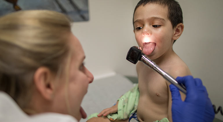 Female doctor looking inside of a little boy