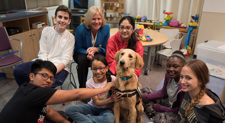 Kids and staff around Paws and Play dog, Professor