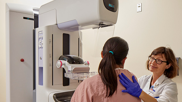 Doctor with woman in dressing down at modern mammography machine