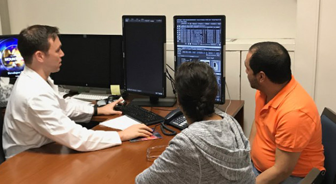 image of physician with patients in office, reviewing data on computer screen