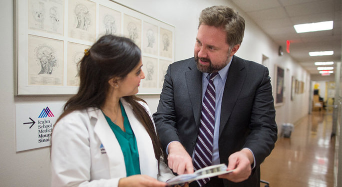 image of Dr. Mocco with faculty reviewing chart in hallway