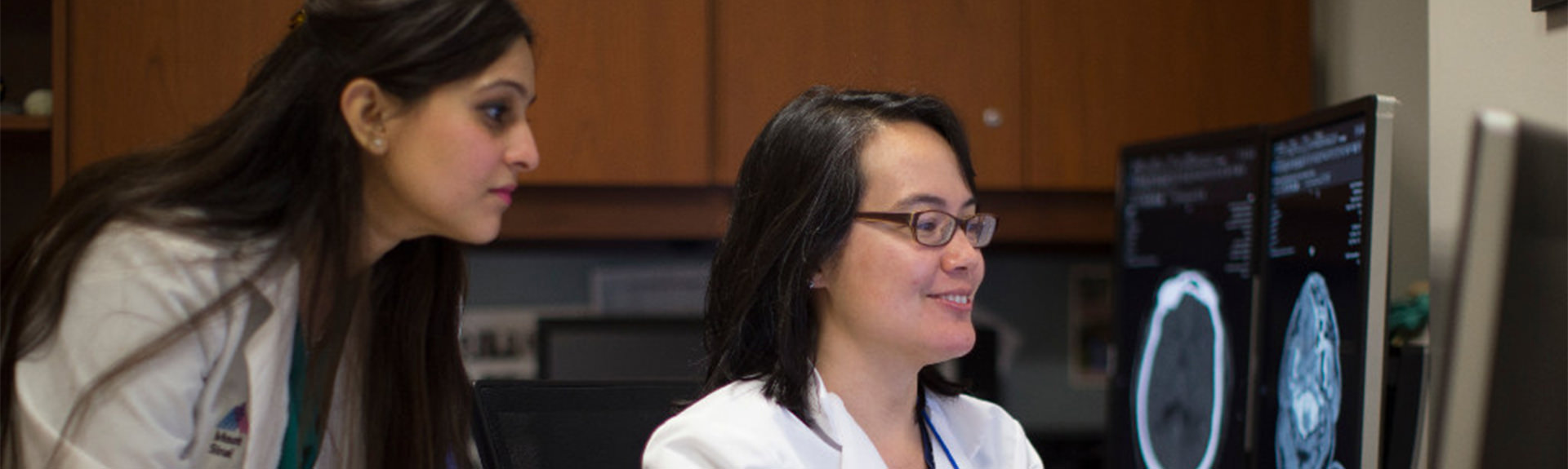 image of Dr. Fifi and faculty member reviewing brain scan on computer screen in office setting