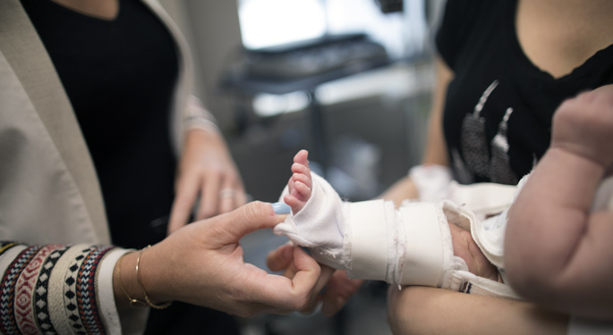 Image of orthopedic surgeon, Dr. Abigail Allen, holding infant patient’s leg.