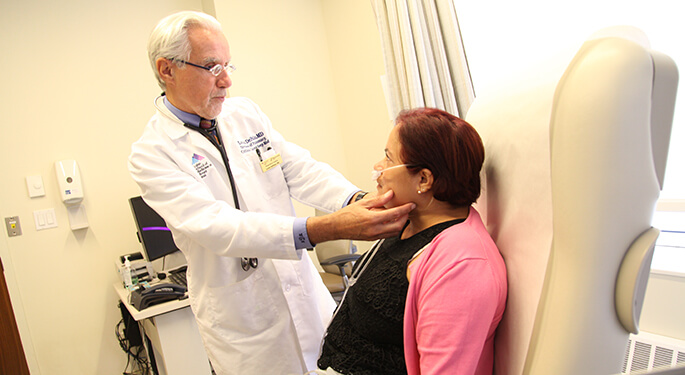 doctor examining patient while she sits in office