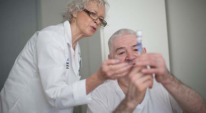 Doctor looks at insulin injection with seated patient 