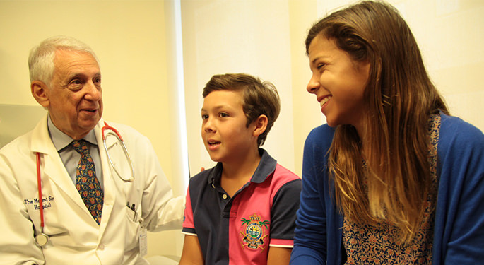 Two pediatric patients speaking with doctor in exam room