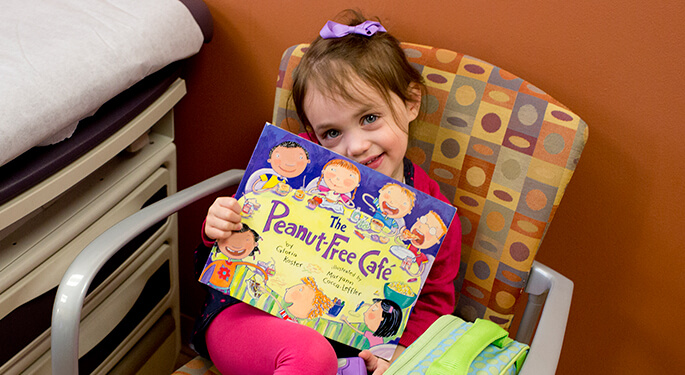 Little girl holding book, Peanut-Free Cafe