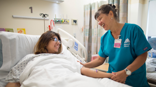 nurse and patient laying on bed smiling at one another