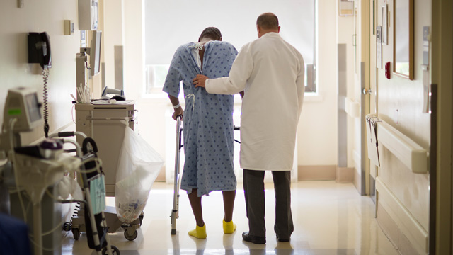 doctor helping patient walk down hallway