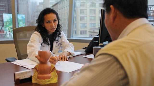 asian doctor sitting across desk from patient