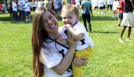 woman smiling to camera while holding a baby