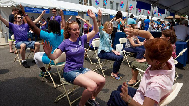 Mount Sinai Queens outdoor event; group stretching while sitting