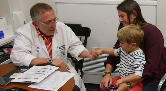 image of Dr. Berenstein with child patient and parent in office setting