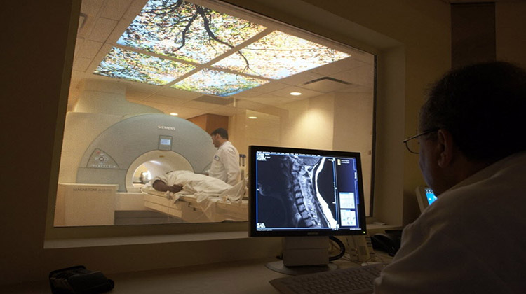 image of patient in MRI scan machine, with a doctor viewing images taken